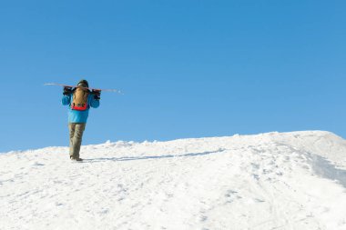 Bir dağın tepesine yürüyüşe kask içinde Snowboarder
