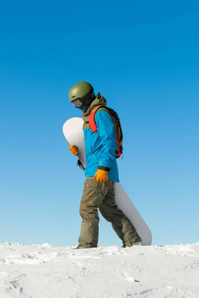 Snowboarder στο κράνος περπάτημα κάτω από την κορυφή ενός βουνού — Φωτογραφία Αρχείου