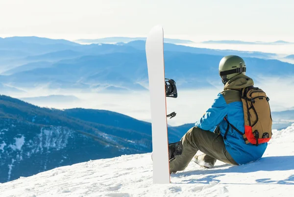 Snowboarder zit op de top van een berg en genieten van het landschap — Stockfoto