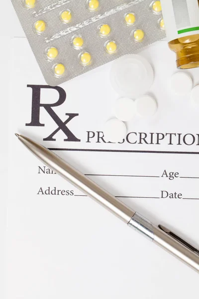 Different pills and silver color pen over medical prescription form — Stock Photo, Image