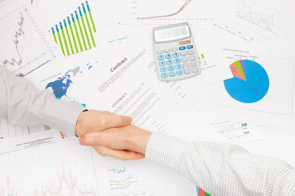 Affärsmän som skakar hand ovanför tabellen med vissa finansiella grafik — Stockfoto
