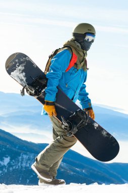 Dağın tepesine yürüyüş kask içinde genç snowboarder