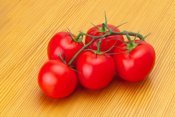 Close up studio shot of bunch of red tomatoes on wooden table — Stock Photo, Image