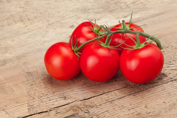 Studio shot of bunch of red tomatoes on rustic wooden table — Stock Photo, Image