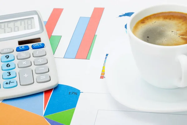 Close up studio shot of a coffee cup and a calculator over some financial documents — Stock Photo, Image