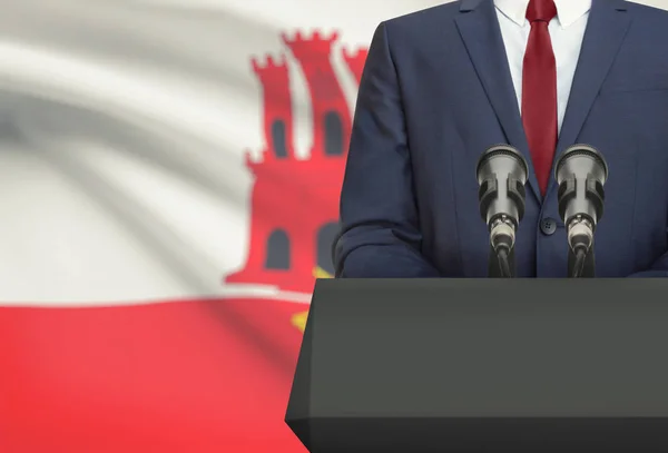 Homme d’affaires ou un politicien faire discours derrière un pupitre avec drapeau national sur fond - Gibraltar — Photo