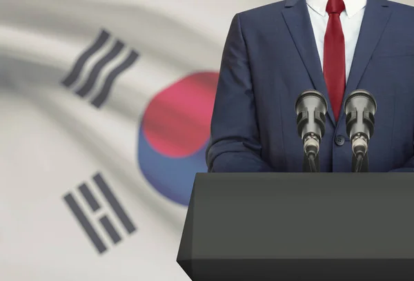 Businessman or politician making speech from behind a pulpit with national flag on background - South Korea —  Fotos de Stock