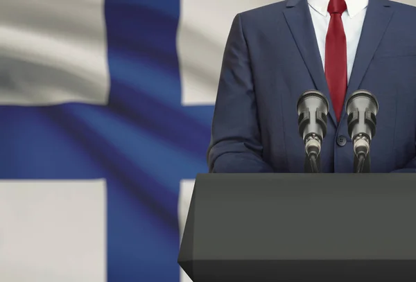 Бізнесмен або політик, роблячи мовлення з амвона з національного прапора на фоні - Фінляндія Ліцензійні Стокові Зображення