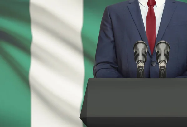Businessman or politician making speech from behind a pulpit with national flag on background - Nigeria — Stock Photo, Image