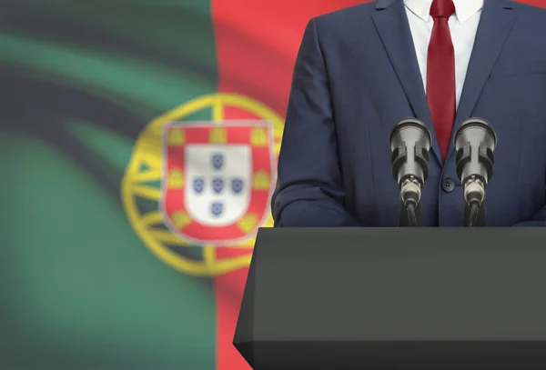 Businessman or politician making speech from behind a pulpit with national flag on background - Portugal