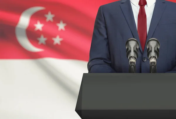 Affärsman eller politiker att göra tal bakom en predikstol med flagga på bakgrunden - Singapore — Stockfoto