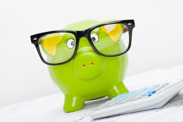 Piggy bank in glazen naast een calculator — Stockfoto