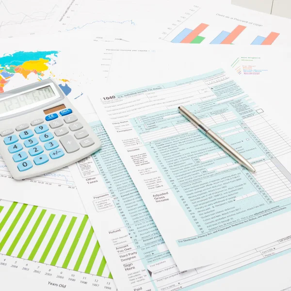 Rekenmachine en pen over ons 1040 belasting formulier en sommige financiële grafieken - close-up studio opname — Stockfoto