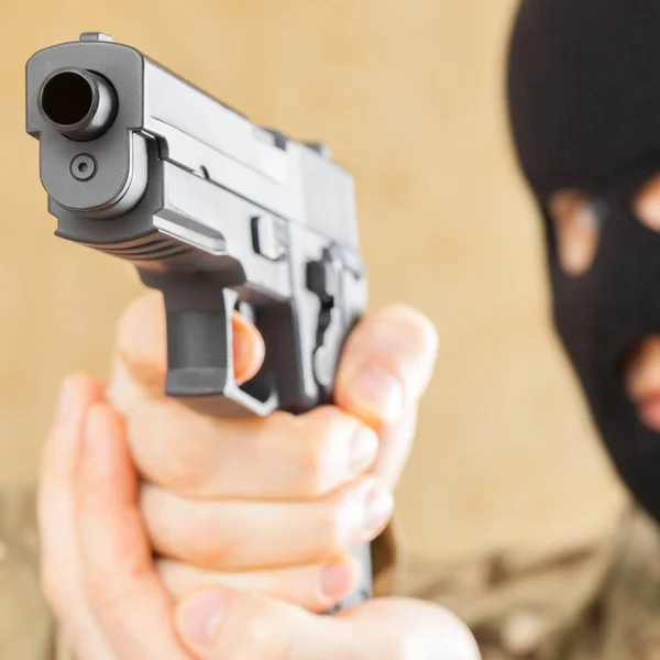 Άνθρωπος στη μαύρη μάσκα εκμετάλλευση όπλο μπροστά του - κοντινό πλάνο στούντιο — Φωτογραφία Αρχείου