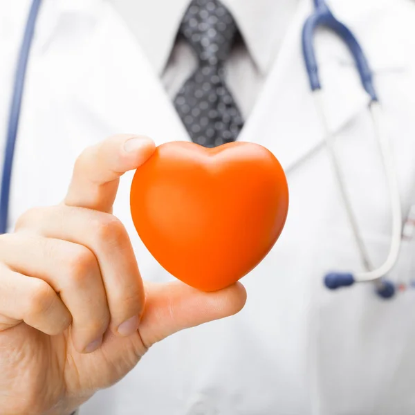 Medicin och sjukvård symboler - läkare håller leksak hjärta med två fingrar — Stockfoto