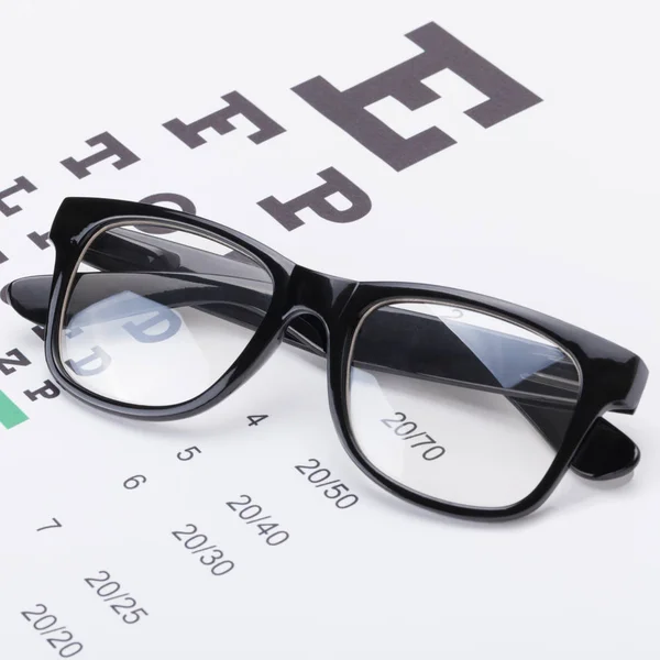 Close up studio shot of a table for eyesight test with neat glasses over it — Stock Photo, Image