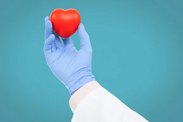Medicina e saúde - médico segurando o brinquedo de coração a luz de fundo azul — Fotografia de Stock