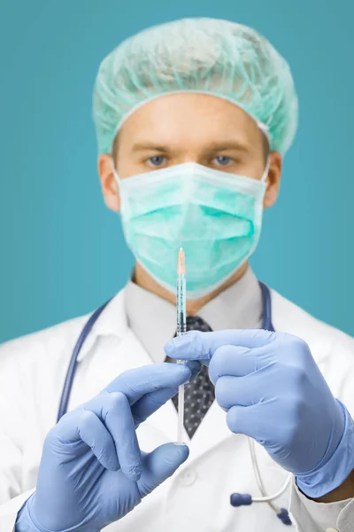 Injekční stříkačka lékaře hospodářství a rozhodnuti injekce na světlo modré pozadí — Stock fotografie
