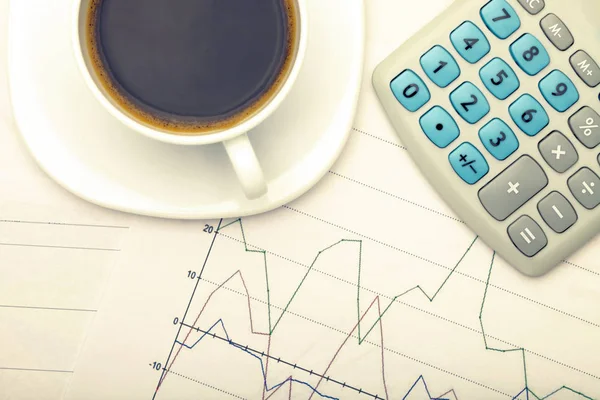 Taza de café y calculadora en gráficos del mercado de valores - vista desde la parte superior. Imagen filtrada: efecto vintage cruzado. —  Fotos de Stock