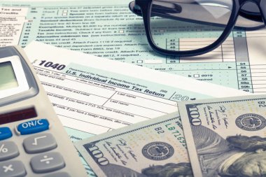 ABD 1040 vergi formu, hesap makinesi, gözlük ve dolar - studio vurdu. Filtre uygulanan görüntü: çapraz işlenen vintage etkisi.