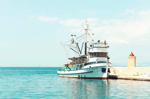 Fishing trawler at a pier next to a lighthouse — Stock Photo, Image