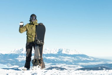 Snowboardcunun elinde boş asansör kartı, diğerinde snowboard kartı var.