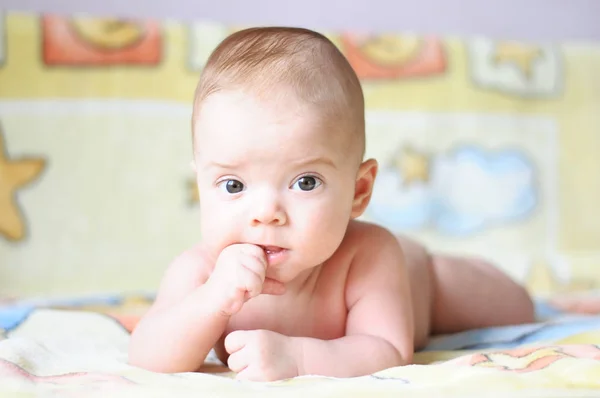 赤ちゃんの黄色の毛布の上に横たわると彼の指を噛んで — ストック写真