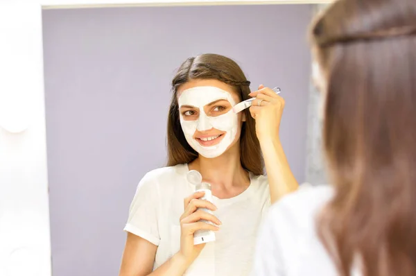 Uma Jovem Mulher Bonita Coloca Uma Máscara Branca Seu Rosto — Fotografia de Stock