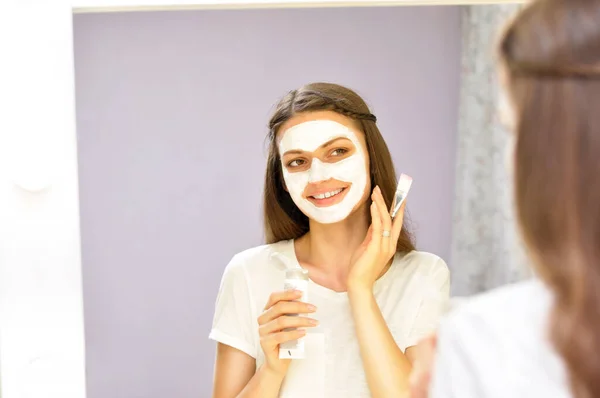 Young Beautiful Woman Puts White Mask Her Cleansed Face While — Stock Photo, Image