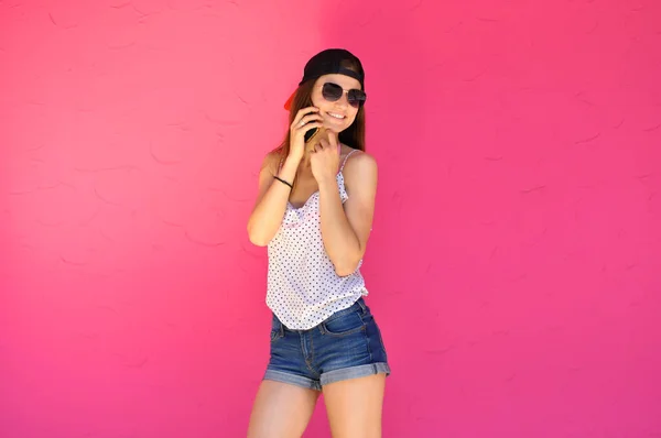 穿着嘻哈风格衣服 戴着太阳镜 拿着智能手机的性感年轻女子 — 图库照片