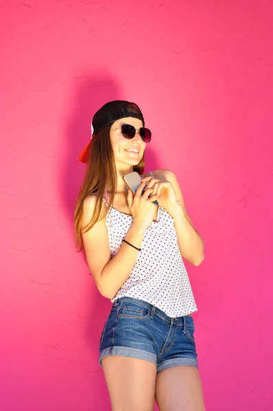 穿着嘻哈风格衣服 戴着太阳镜 拿着智能手机的性感年轻女子 — 图库照片