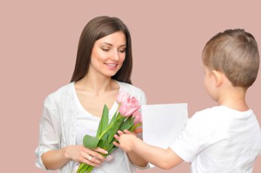 Küçük çocuk annesine bir buket pembe lale veriyor. Anneler Günü kutlaması.