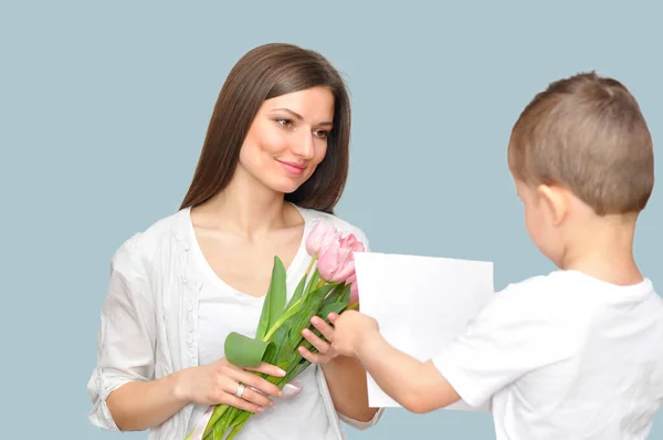 Little child son gives his mother a bouquet of delicate pink tulips. Mother\'s Day celebration.