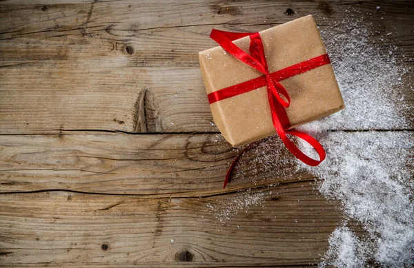 Christmas Present verpakt in Kraft papier op een houten achtergrond — Stockfoto