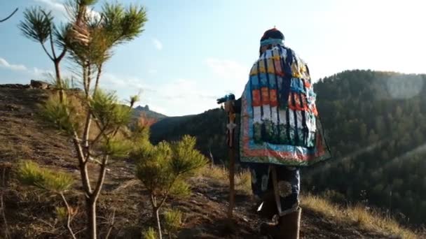 Geleneksel şaman kostümlü bir orman büyücüsü orman yolunda yürüyor.. — Stok video