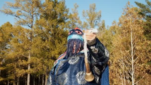 Un vecchio sciamano in costume tradizionale scuote una campana . — Video Stock