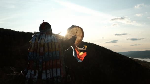 O feiticeiro entra em um transe batendo um pandeiro ao pôr do sol . — Vídeo de Stock