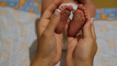 Bebeklerin bacaklarını tutan genç bir kadının ellerini yakından çek..