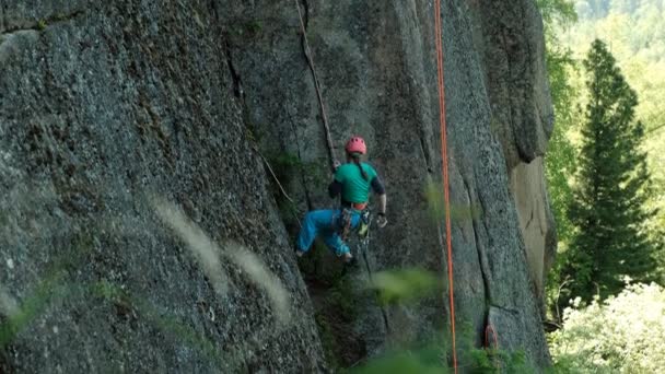 Una joven desciende del acantilado en una cuerda . — Vídeos de Stock