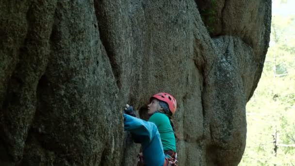 A young woman climbs a difficult route on a vertical wall. — Stock Video