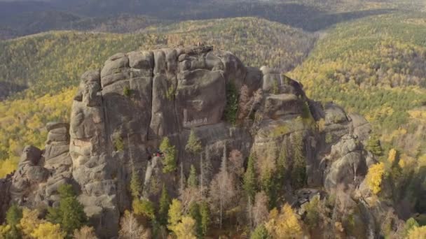 Krasnoyarsk, Rusya - 1 Kasım 2019: Stolby Sibirya ulusal yaban hayatı sığınağındaki İkinci Sütun Dağı 'nın havadan görünüşü. Krasnoyarsk Stolbism 'in bir sembolü olan granit kayanın üzerindeki yazıt.. — Stok video