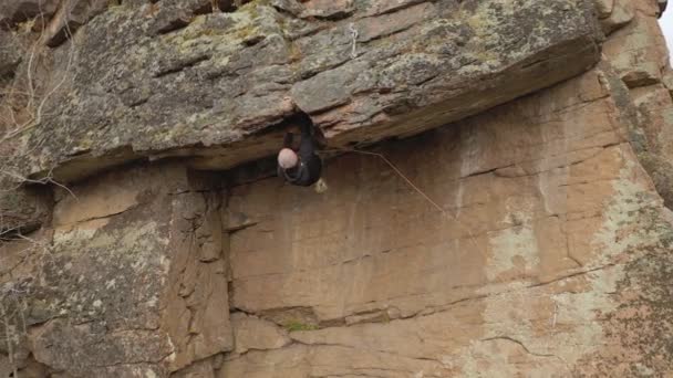 A strong man takes a difficult route on a steep cliff. — Stock Video