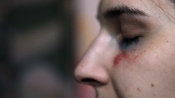 一名遭受暴力创伤的年轻妇女脸上的一滴泪的特写. — 图库视频影像