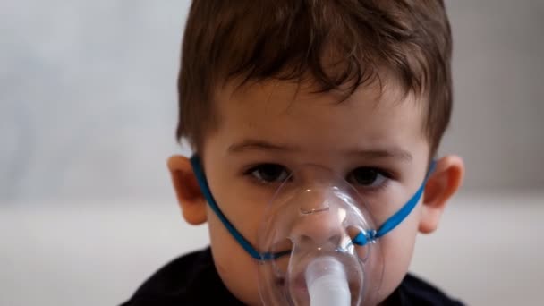 Close up portrait of a sad little boy in a medical mask for inhalation. — Stock Video