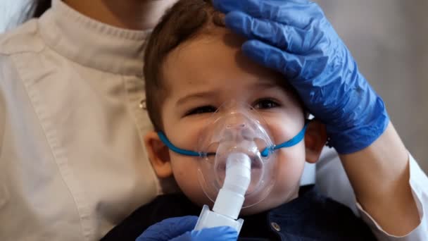 Slow motion porträtt av en ledsen liten pojke i en medicinsk mask, läkaren försiktigt smeka barnen huvudet. — Stockvideo