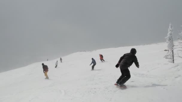 Movimento lento de um grupo de esquiadores e snowboarders nas encostas da estação de esqui . — Vídeo de Stock