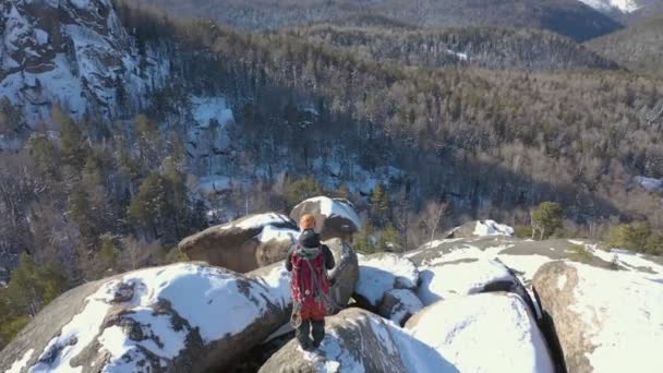 Luchtfoto van een eenzame mannelijke klimmer op een besneeuwde bergtop. — Stockvideo