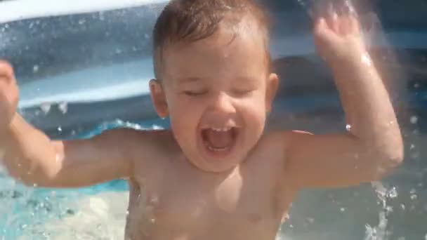 A small white child splashes in the pool in summer. — Stock Video
