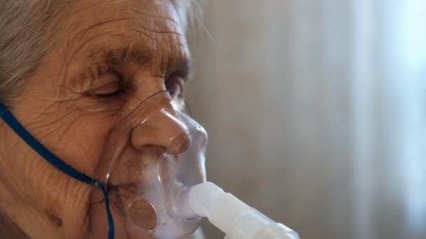 Primer plano de una anciana con los ojos cerrados usando una máscara de respiración médica . — Vídeos de Stock