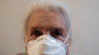 Maskeli, yaşlı, gri saçlı bir kadının yüzüne yakından bakın..
